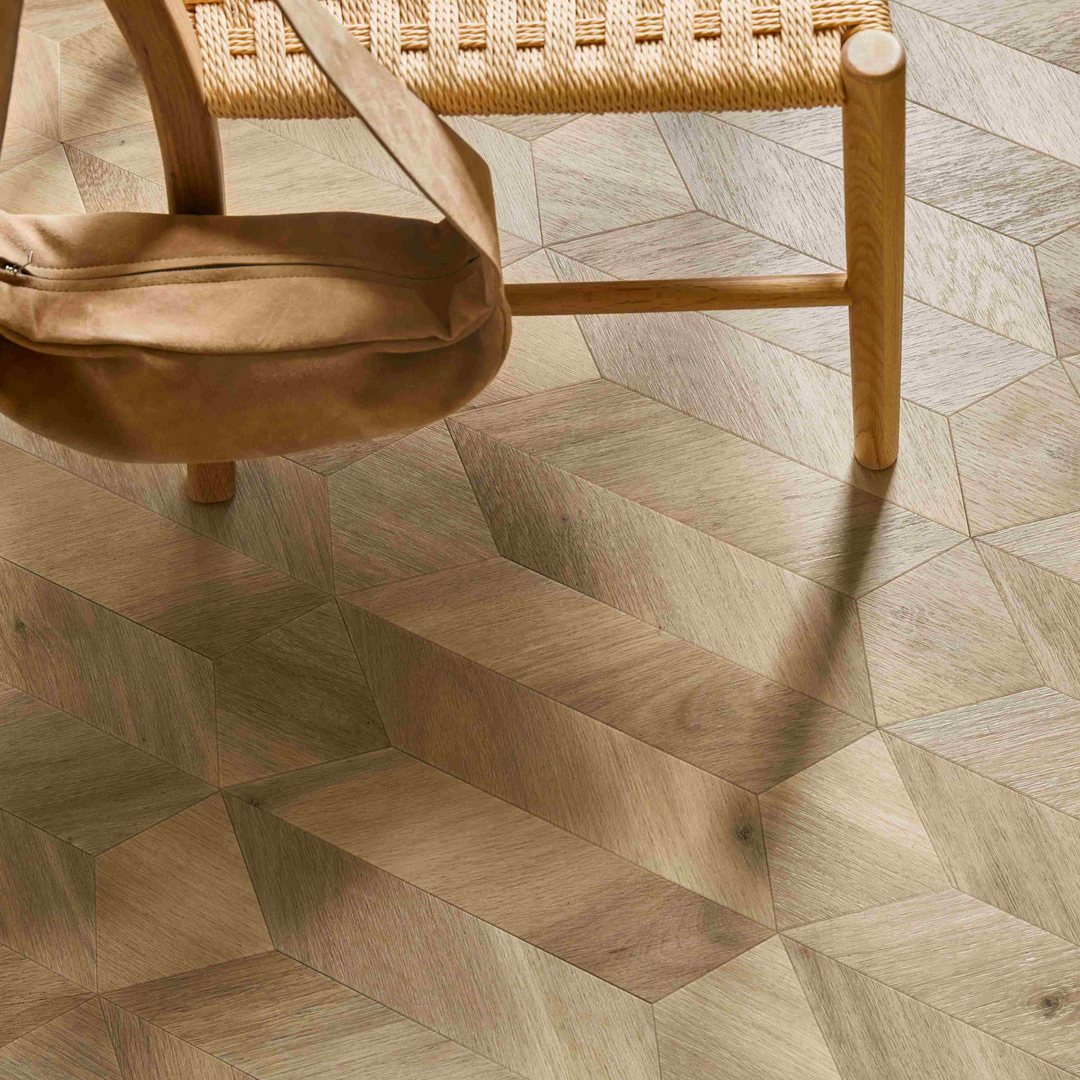 Woven chair and beige handbag on a wooden floor with a herringbone pattern