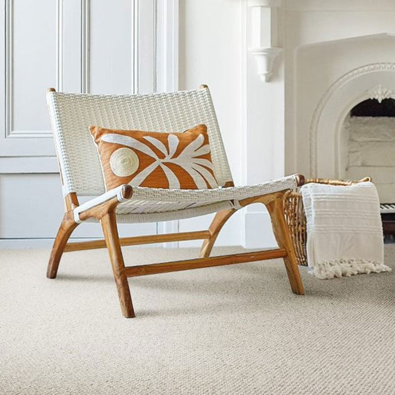 Woven chair with a decorative pillow and blanket in a room with a fireplace.