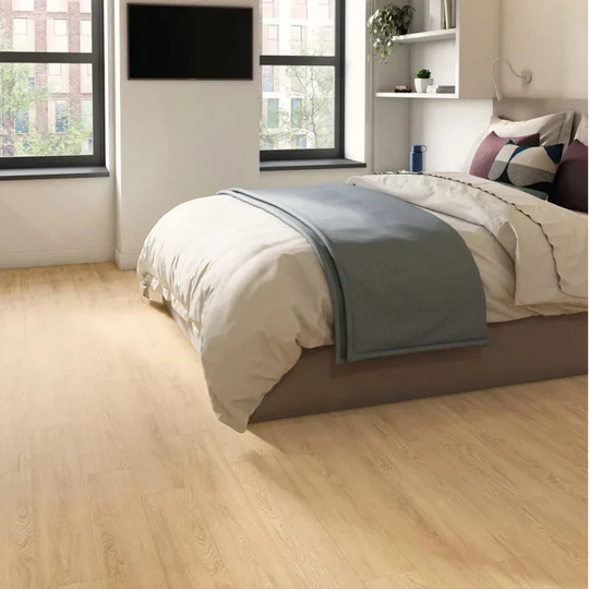 Modern bedroom with wooden flooring, bed, and kitchen area.