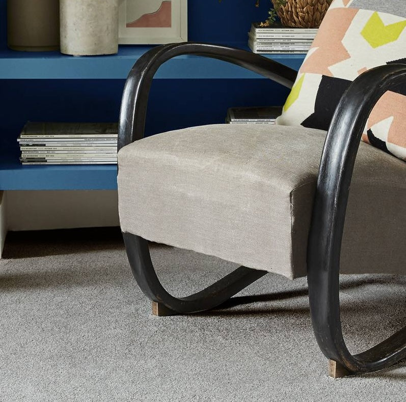 Gray armchair with black metal frame in a room with a blue shelf and decorative items.