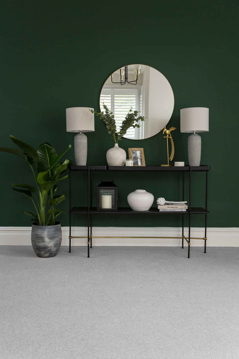 Modern interior design with a round mirror, lamps, and decorative items against a green wall.