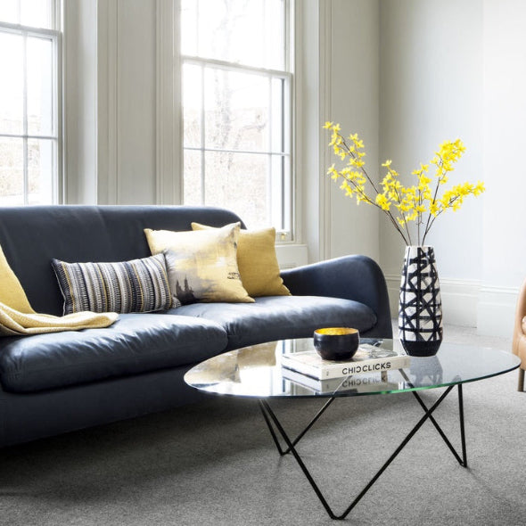Modern living room with a blue sofa, yellow cushions, and a coffee table.